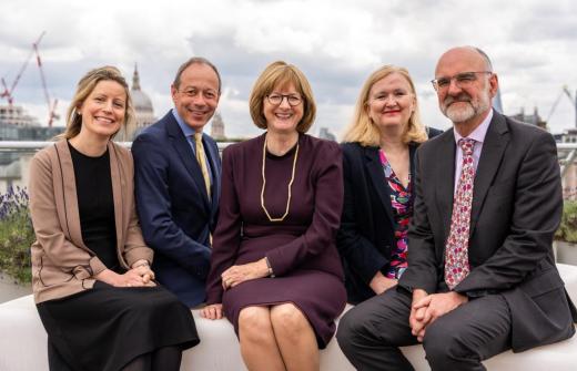 Five lawyers sit side-by-side and smile at the camera.
