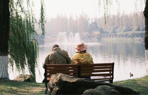 A couple sitting on a bench looking out at a lake
