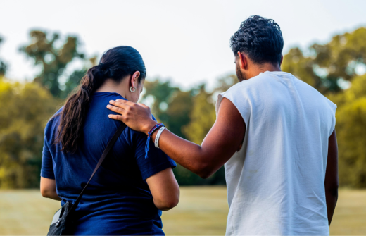 A man with his hand on a womans shoulder as a sign of support