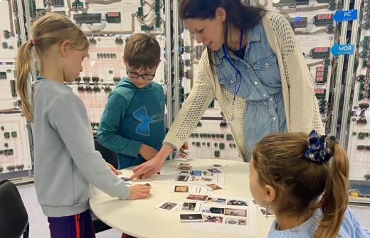 A volunteer helps a group of children create a timeline using photos of items from computing history 