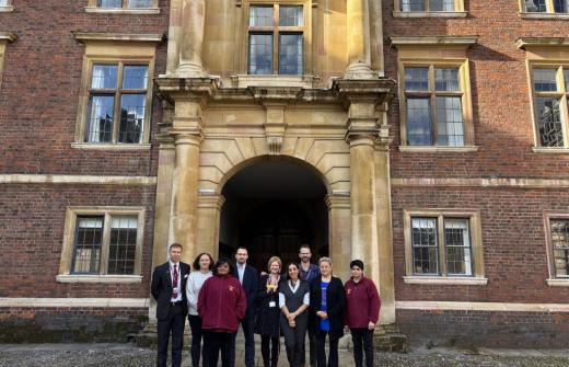 St Catharine's College team in Cambridge standing outside an old part of the college with red brick & yellow arch way