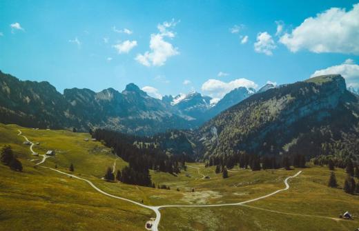 Pathways along grass hillsides with mountains in the distance