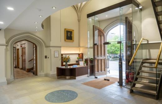 Refurbished reception area at Pitt Building, Cambridge. Glass doors opening up from the street into the foyer which is light and bright but retains an element of traditional Cambridge venue