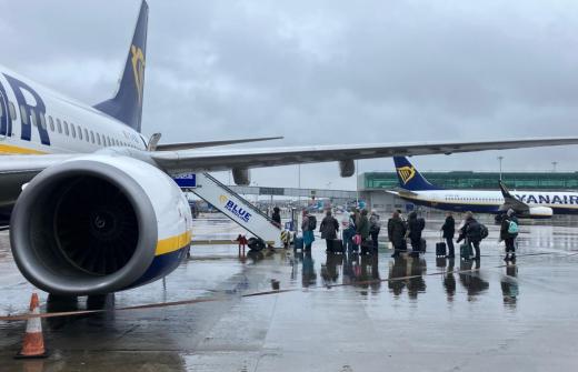 A queue of passengers waiting to board a Ryanair plane in the rain