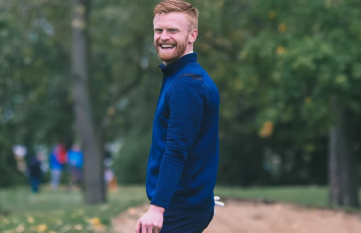 man stands smiling on golf course