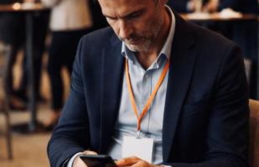 A man intent on his phone, ignoring all else around at a busy networking event