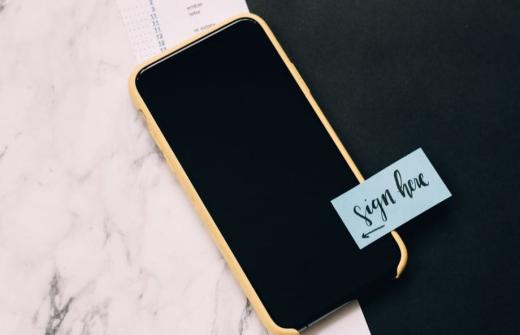 A mobile phone with a written note on it saying sign here.