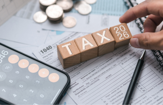 Letter blocks spelling out tax, with a calculator open on a phone