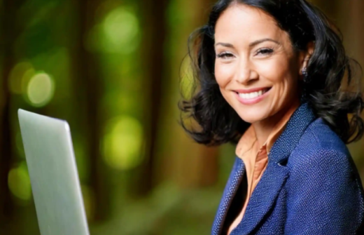 Smiling professional woman sitting outdoors with a laptop, representing confidence and learning. Text on image reads “HR Training Guide – Upskilling Your Team with Confidence. enjoy learning