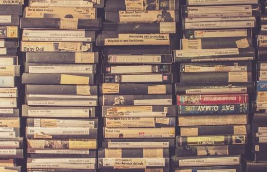 Stacked VHS tapes with handwritten labels, representing legacy media being preserved through digitisation.