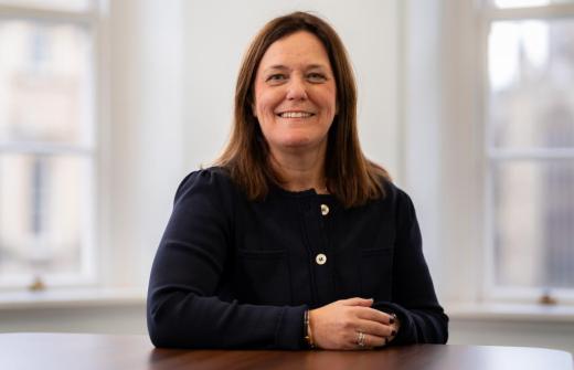 Waist-up photo of Stone King CEO, Vicky Brackett, sitting at a table and smiling.