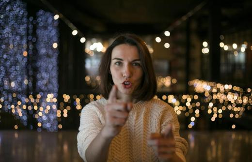 A woman pointing directly at the viewer