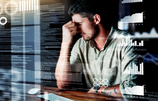 man with head in hands overwhelmed by lots of images of data around him