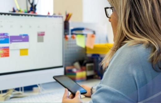 Woman looking at  mobile phone and calendar on her computer screen