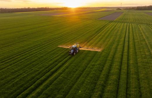 Tractor in a field with the sun setting in the distance 