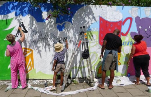 Five people painting on a wall