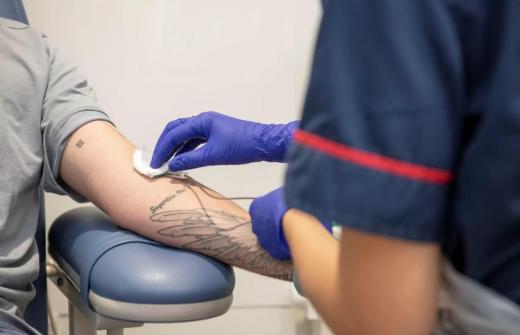 Photo of patient's arm providing a blood sample, with nurse's hand carrying out the procedure