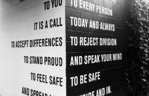 a white wall with the words it is a call to accept differences to stand proud to feel safe and a black wall with today and all ways, to reject division, and to speak your mind, to be safe