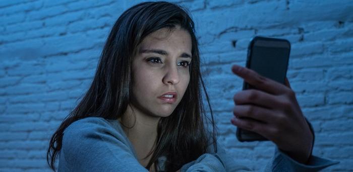 Girl stares at mobile phone and looks upset