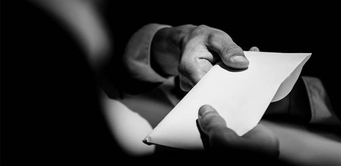 Hands giving and receiving an envelope with a 'bribe'
