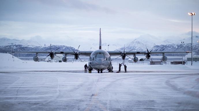 Large propeller plane on runway with snowy mountains