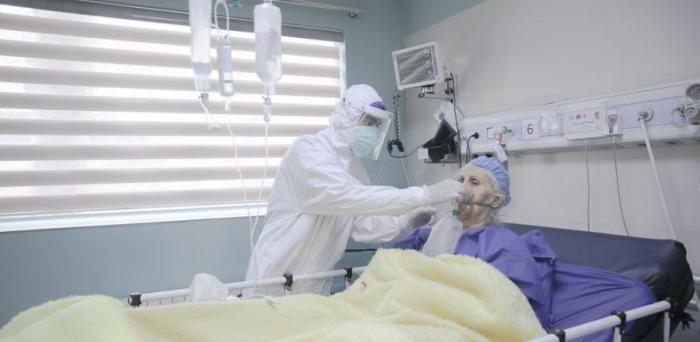   A clinician helping a COVID-19 patient with an oxygen mask in a hospital in Iran  Credit: Mehrnews.com