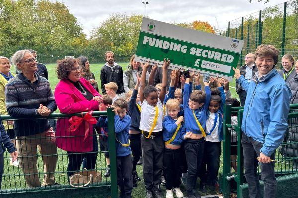 children holding a cheque on a sports field