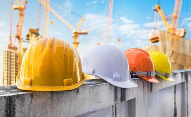 hard hats on a construction site with cranes in the background