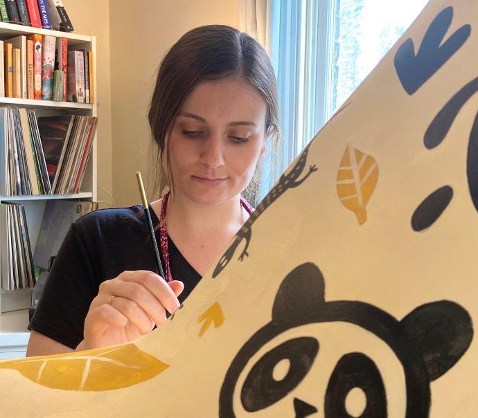 Alice Courtley painting the ARU giraffe