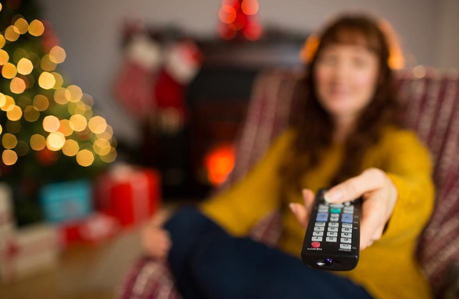 A female holding a remote control pointing it at a tv