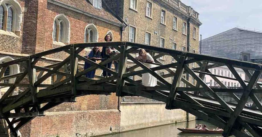 Three people stand on the Mathematical Bridge, smiling
