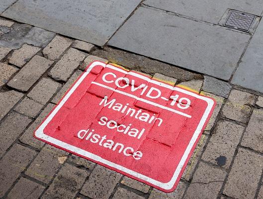 Covid - social distancing sign on pavement
