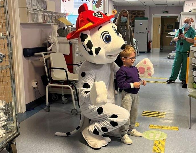 someone in dog costume hugging a child in hospital 