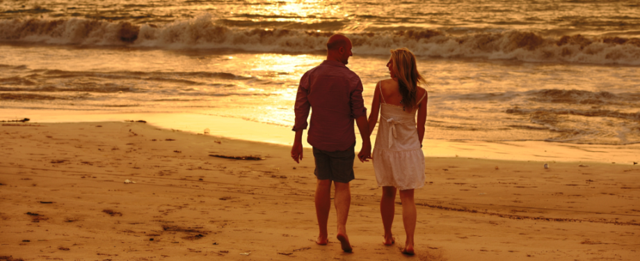 A couple walking on a beach at sunset