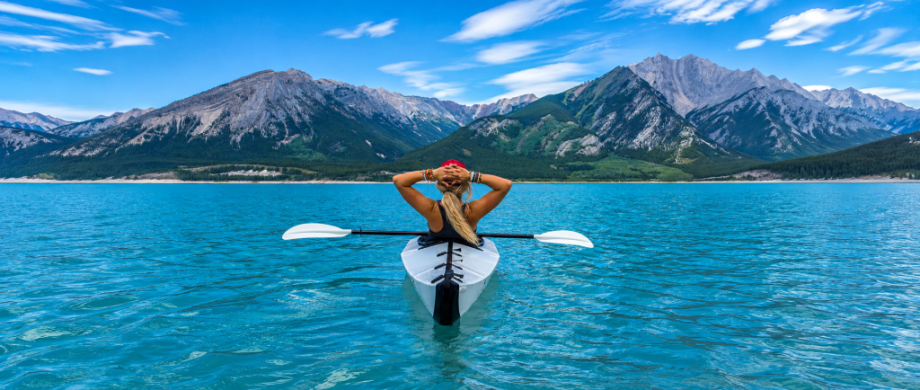 A woman on a kayak overlooking mountains