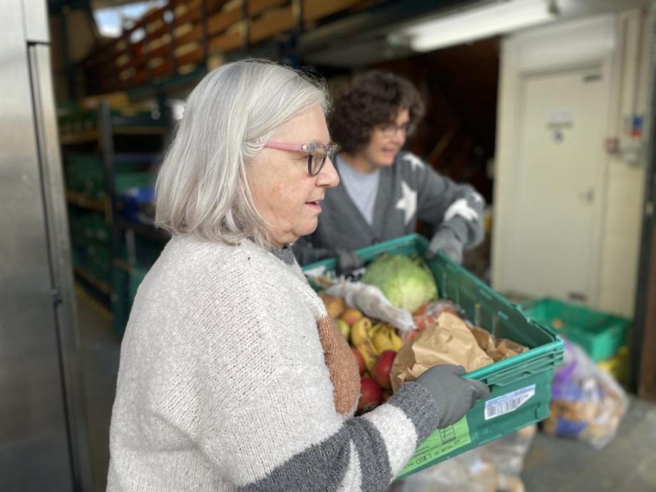 Volunteers at the Cambridge Sustainable Food warehouse moving a crate of vegetables