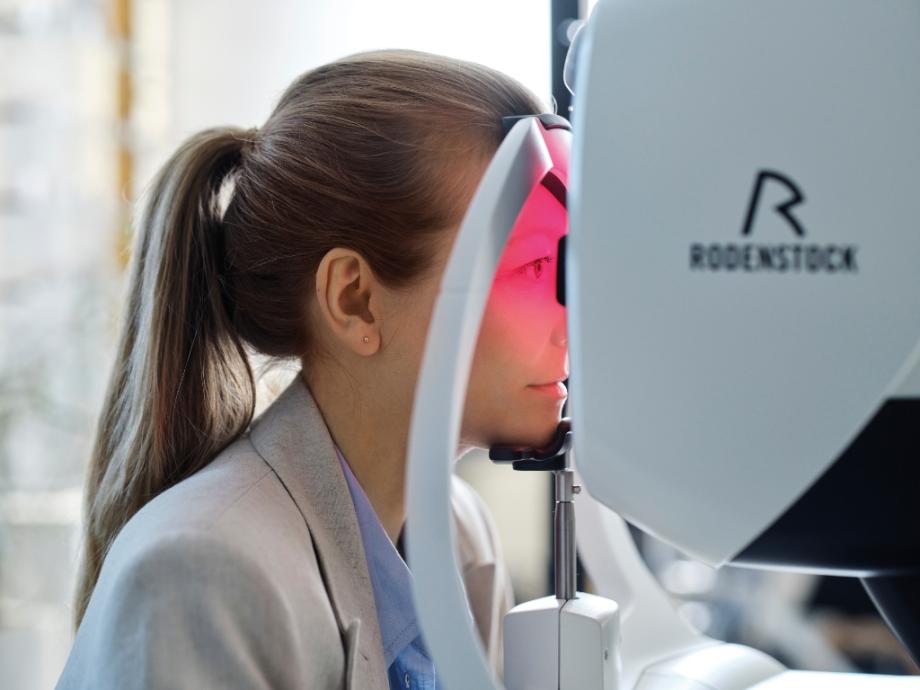 Female patient using Rodenstock eye scanner during eye exam