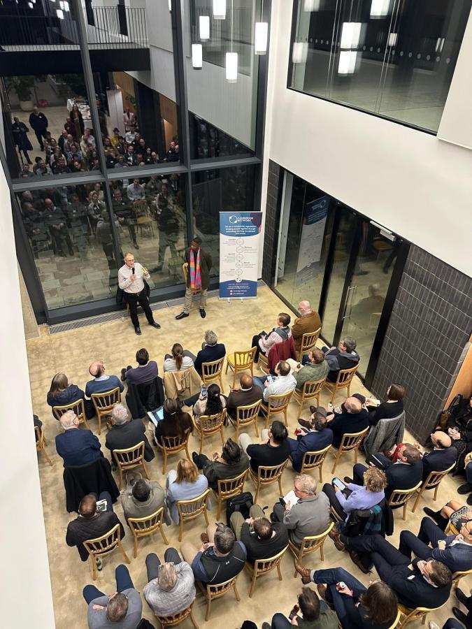 2 speakers talking to a seated crowd