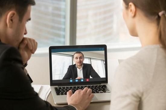 Two people in Zoom conversation with a man on the screen
