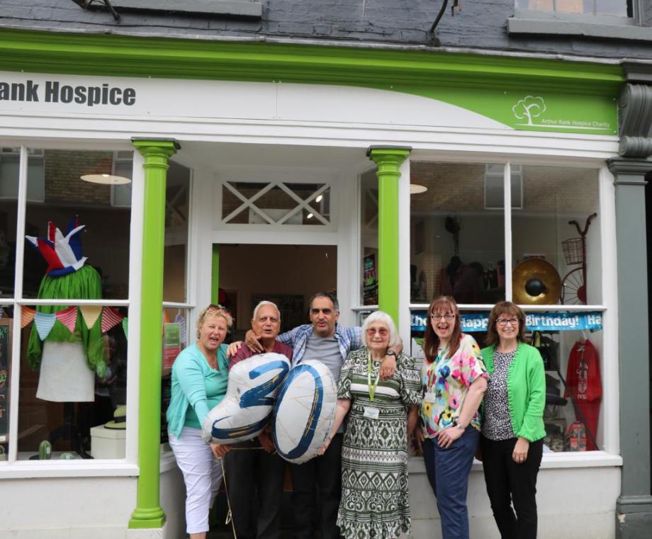 Males and females outside a shop with a balloon