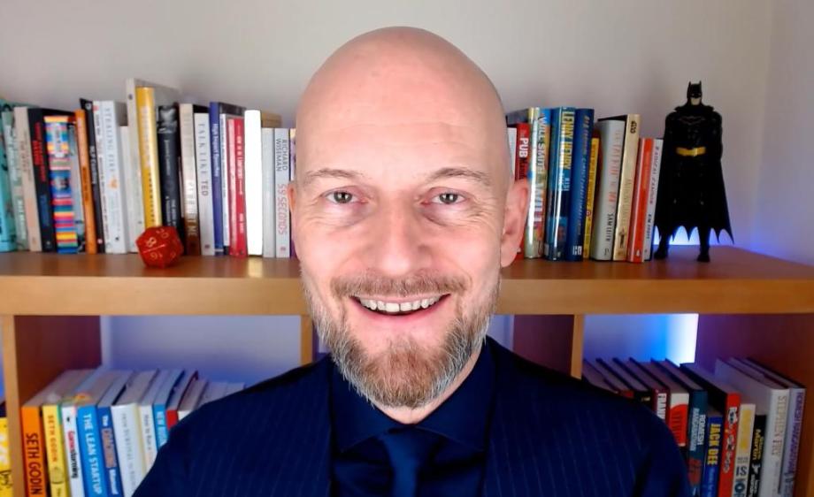 Smiling bald man in front of a bookcase