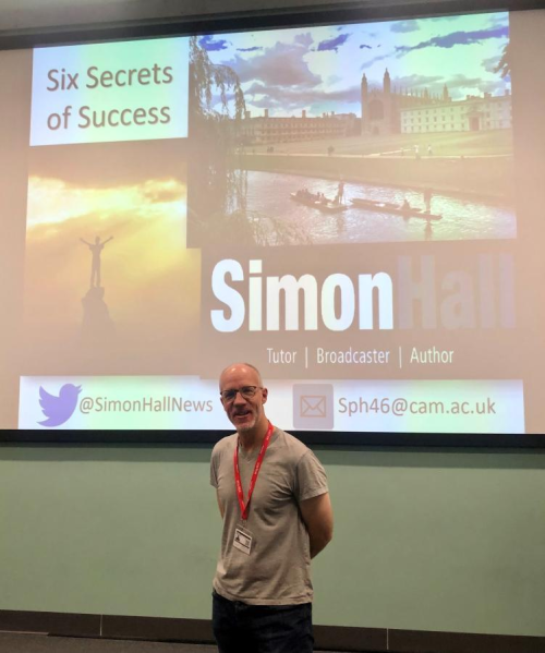 Simon in front of screen with Six Secrets of Success written on it