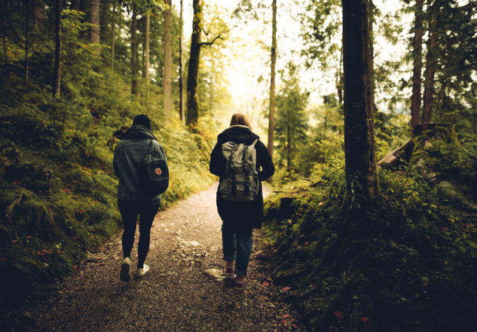 2 people walking in a woods 
