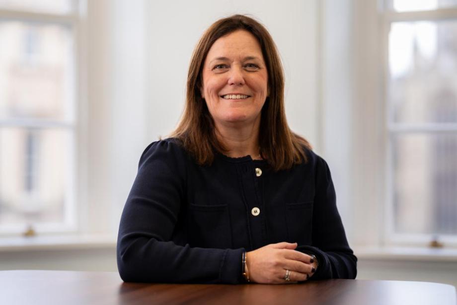 Waist-up photo of Stone King CEO, Vicky Brackett, sitting at a table and smiling.