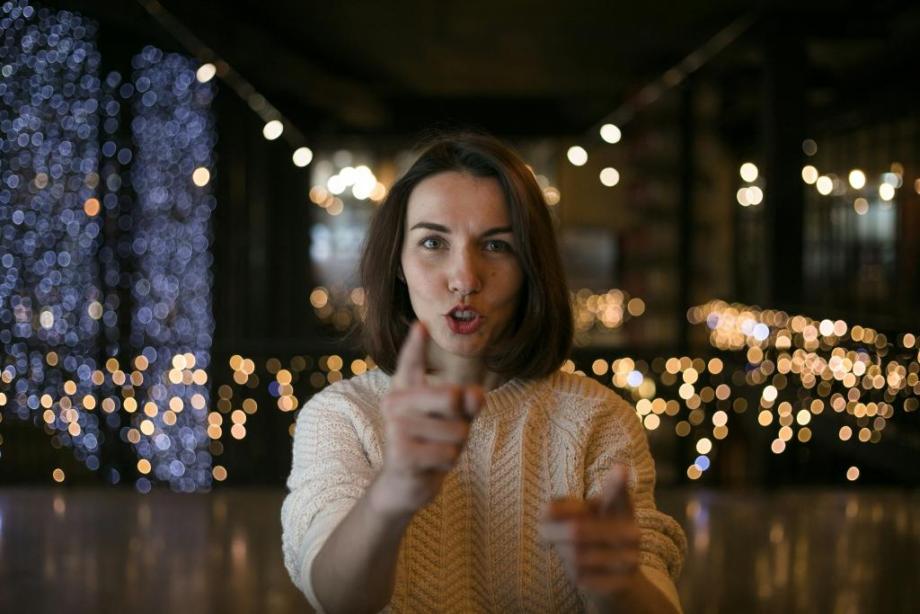 A woman pointing directly at the viewer