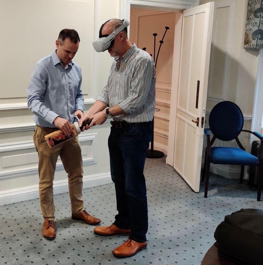 Simon being shown how to play virtual reality cricket while wearing headset