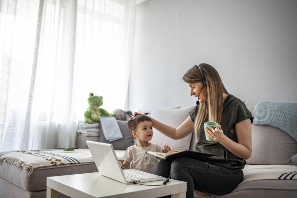 Mother working at home with laptop, headphones - and child