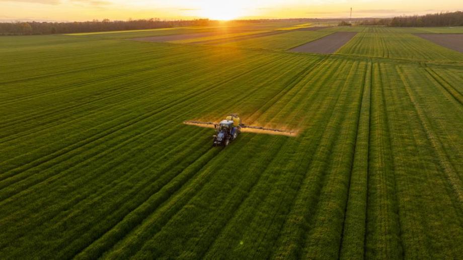 Tractor in a field with the sun setting in the distance 
