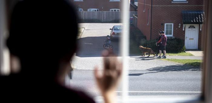   Young boy peers out of his bedroom window during the coronavirus lockdown in the UK in April.  Credit: Benjamin Cooper