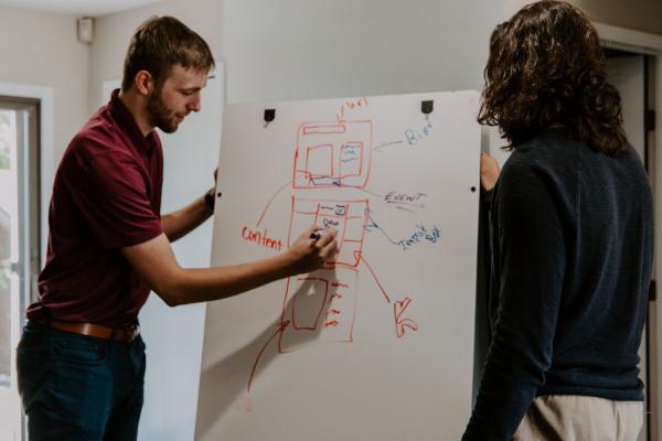 Man explaining diagrm on white board to a woman